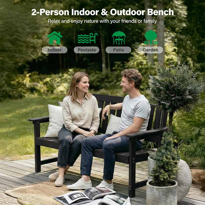 Two people sitting on a 2-person indoor & outdoor bench in a garden setting.