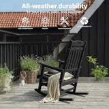 Black rocking chair on a wooden deck with plants and a house in the background, emphasizing durability for outdoor use.