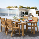 Wooden outdoor dining set with table and chairs on a deck, featuring a modern house and pool in the background.